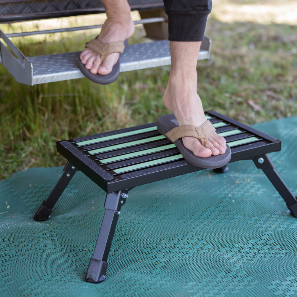Person using a portable footrest on a grassy area