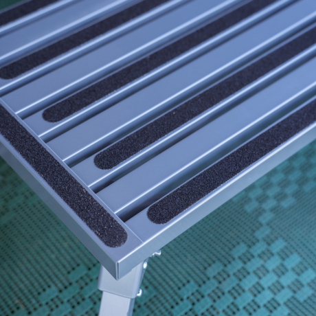 Metallic surface with black rubber strips on a green textured background
