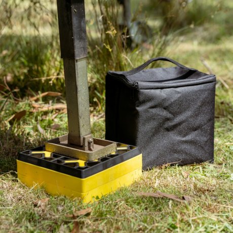 Yellow and black portable stand with a black carrying bag on grass