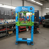 Blue and green hydraulic press with 'TQ Pro' branding in a workshop setting.