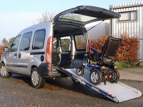 Power wheelchair on a fitted aluminium ramp at the back of a van