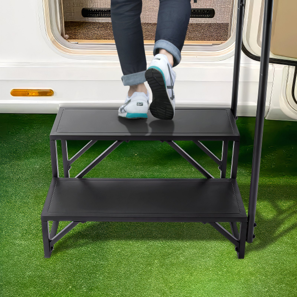 Person using a black step stool to climb into a vehicle on a grassy area.