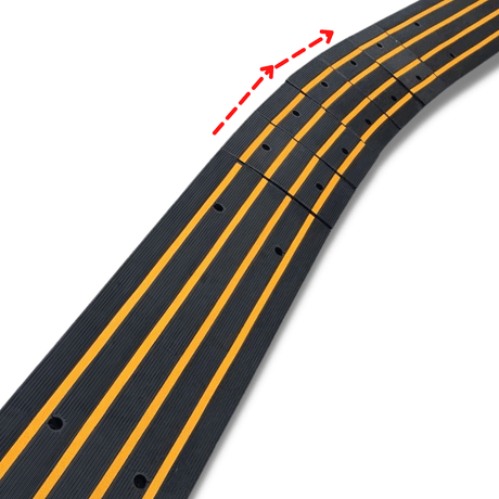 Close-up of a modular black ramp with yellow stripes; red arrows indicate the curved flexibility of the segments.